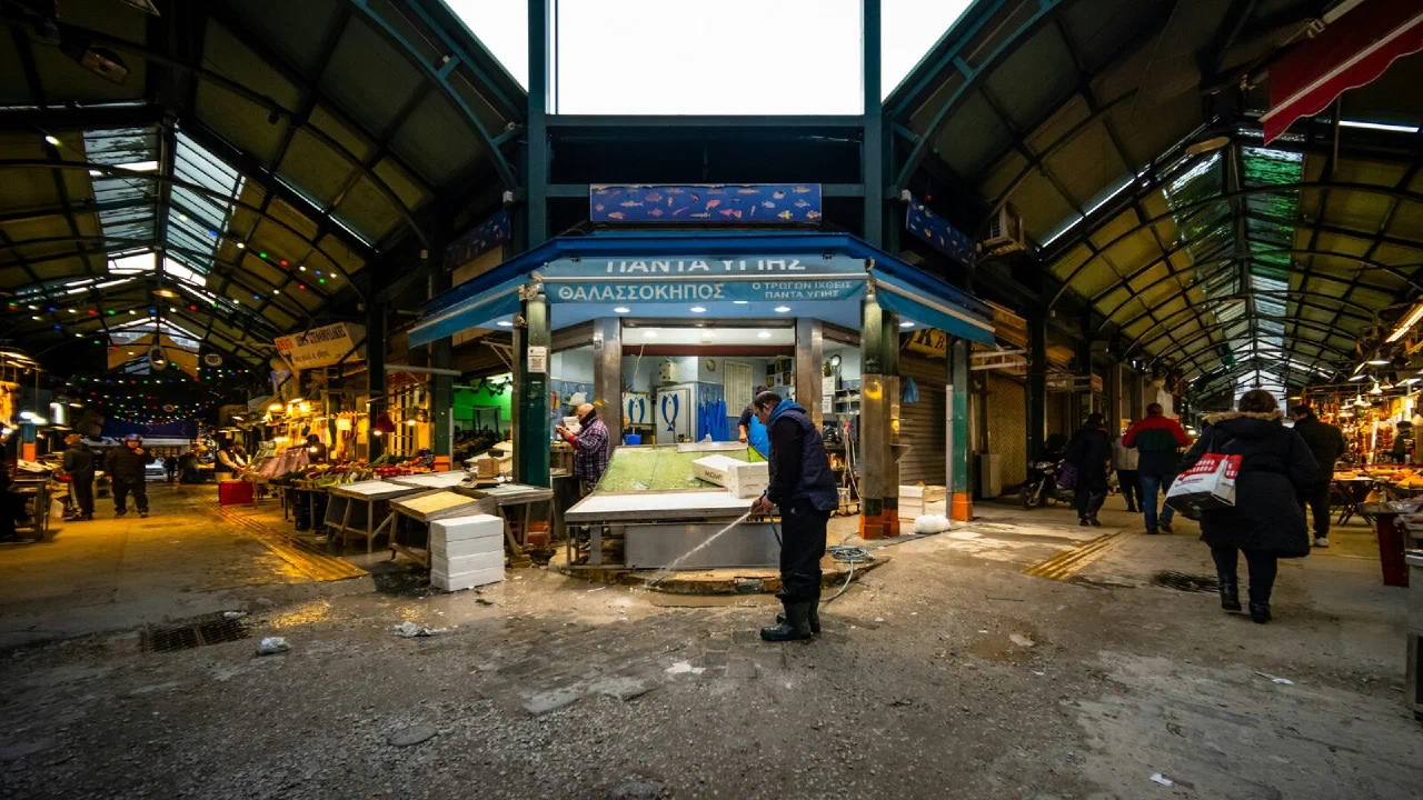 A man sweeping the floor of an open-air market between the stalls