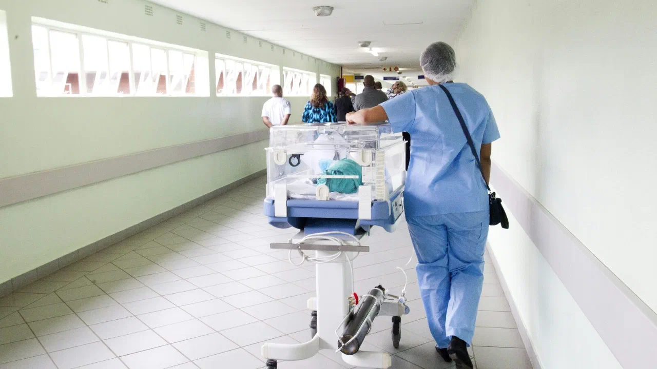 A person in blue scrubs walking down a hospital corridor