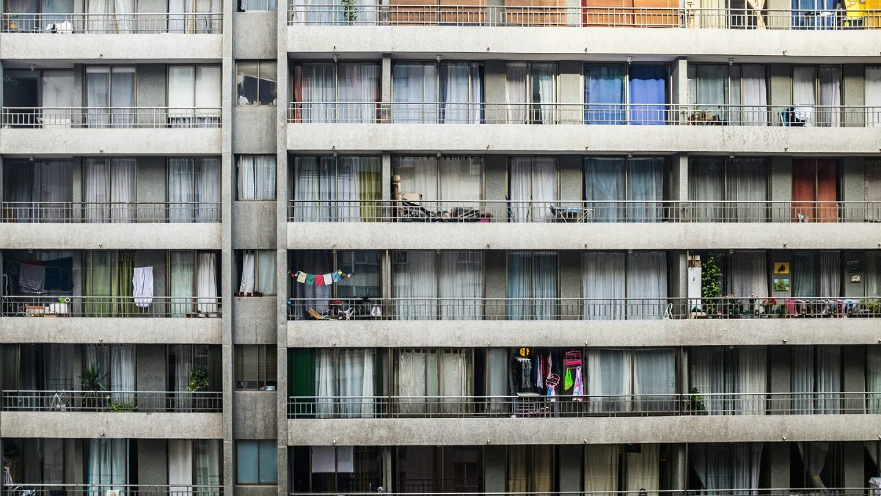 The front of a tall apartment block seen from street level