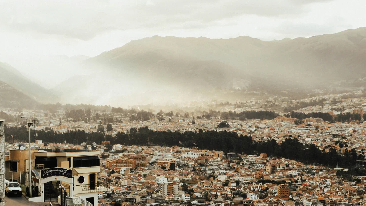 Cuenca seen from a hillside, rooftops filling the valley under hazy Andean ridges