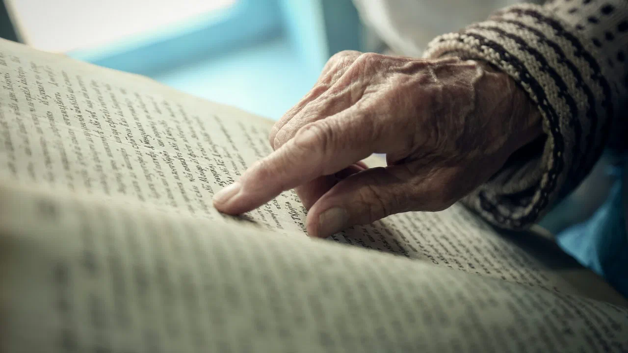 An older person's hand resting on white cloth