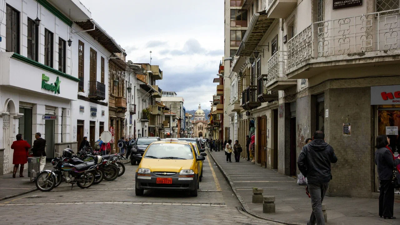 A street of low balconied buildings with a car parked at the kerb
