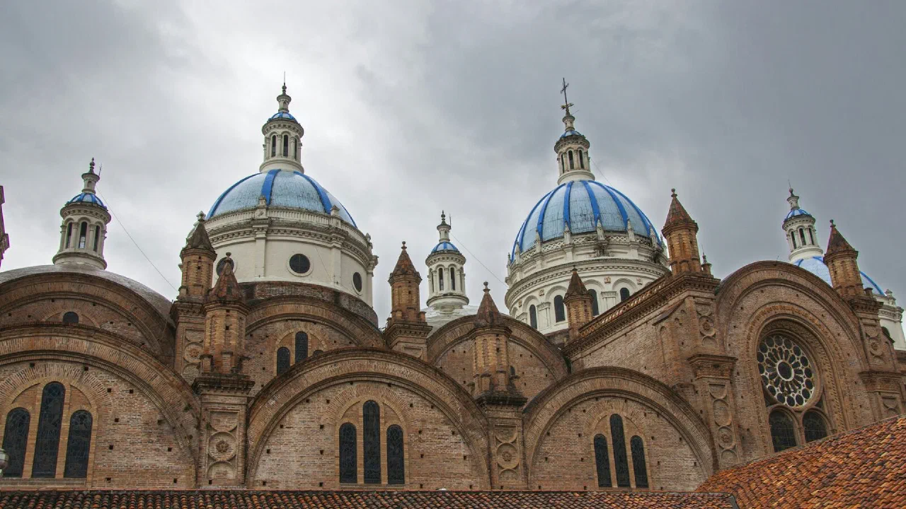 The domed towers of Cuenca's cathedral rising above the rooftops under a grey sky