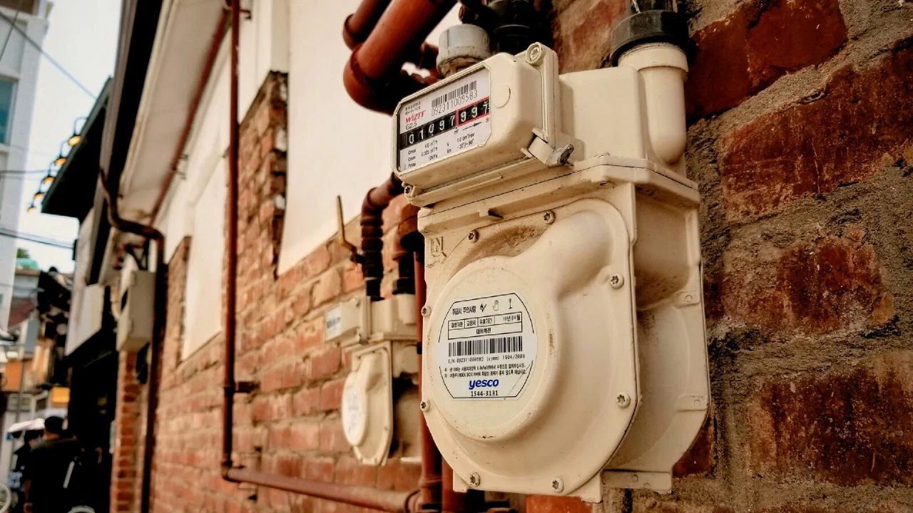 A beige electricity meter mounted on a dark wall